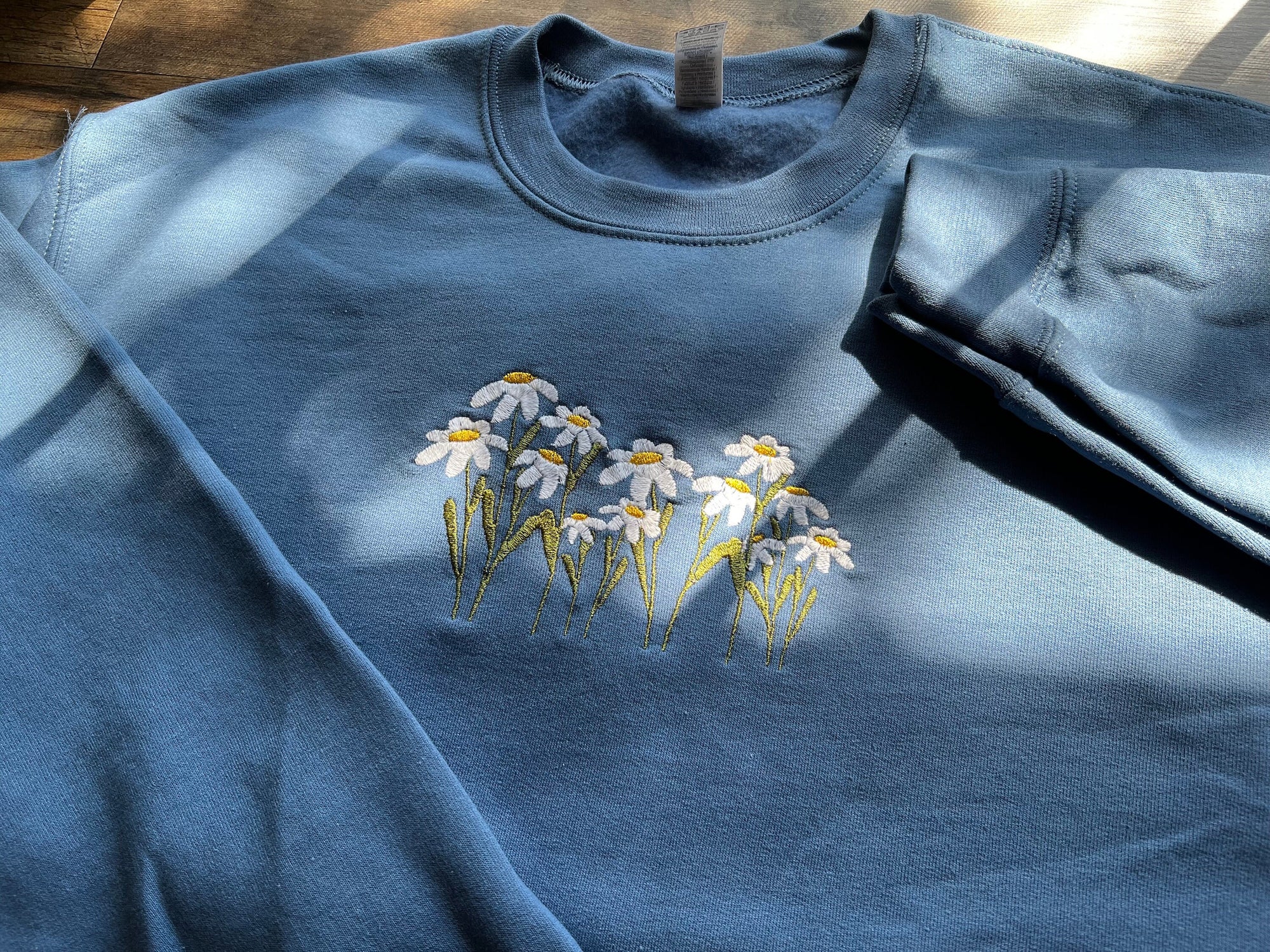 Indigo blue crewneck sweatshirt with embroidered wildflower design in the center.