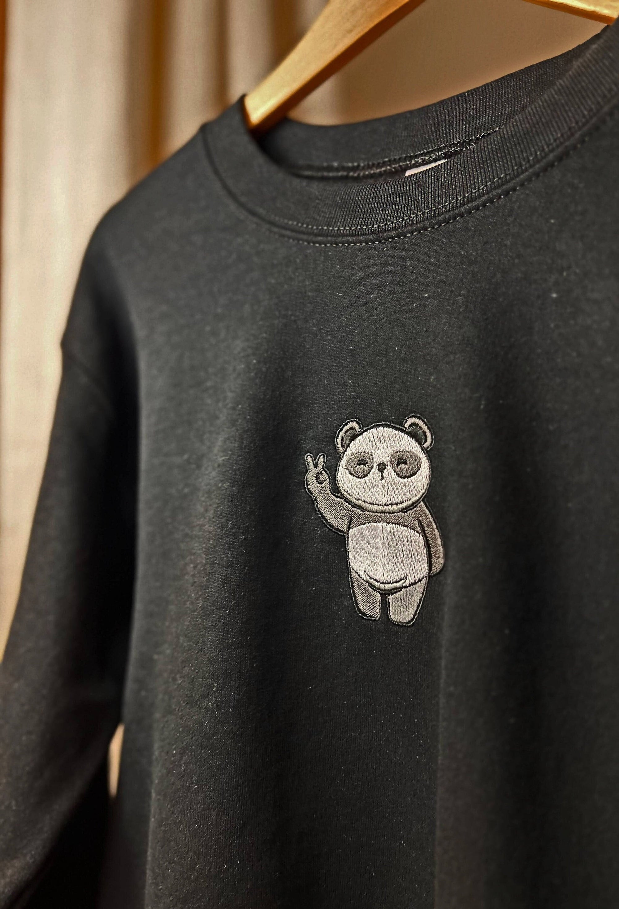Black sweatshirt with a embroidered panda design on the chest.